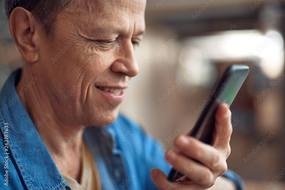 Smilig mature man looking on mobile phone Smilig mature man looking on mobile phone