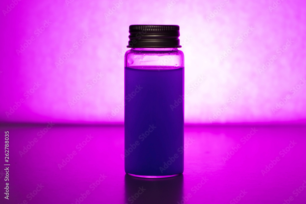 Glass jar with colored liquid on a purple background Glass jar with colored liquid on a purple background
