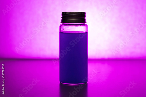 Glass jar with colored liquid on a purple background