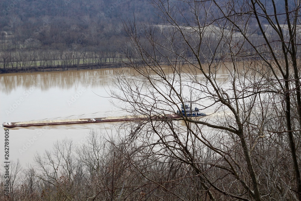 The barge vessel going up the river though the trees. The barge vessel going up the river though the trees.