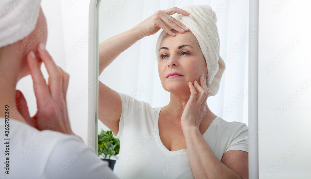 Middle aged woman looking at wrinkles in mirror. Plastic surgery and collagen injections. Makeup. Macro face. Selective focus on the face. Middle aged woman looking at wrinkles in mirror. Plastic surgery and collagen injections. Makeup. Macro face. Selective focus on the face.