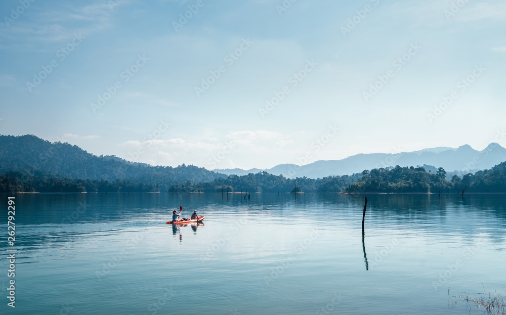 Mother and son floating on kayak together on calm water of Cheow Lan lake in Thailand