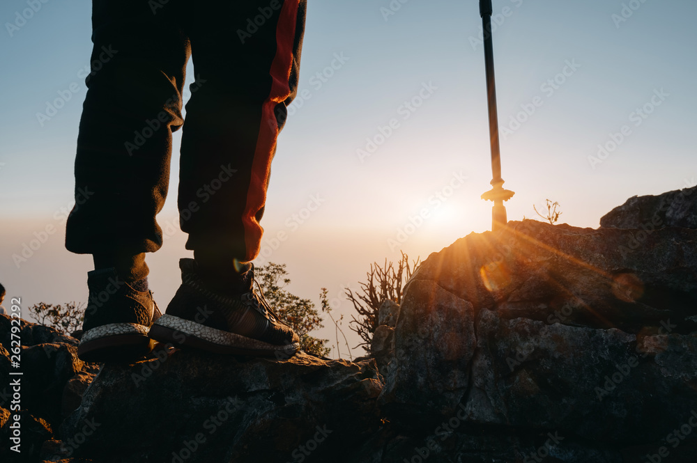 Close up legs of hiking man stand on mountain with sun light.
