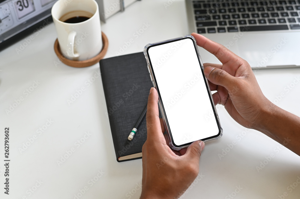 Cropped shot hands using mockup smartphone on office desk with clipping path. Cropped shot hands using mockup smartphone on office desk with clipping path.