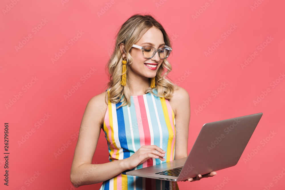 Excited young woman posing isolated over red coral background using laptop computer. Excited young woman posing isolated over red coral background using laptop computer.