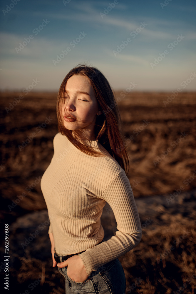 beautiful woman with brunette hair in casual clothes posing in sun rays on background of awesome landscape beautiful woman with brunette hair in casual clothes posing in sun rays on background of awesome landscape