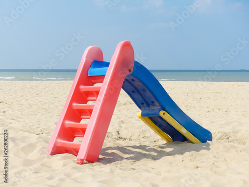 playground slide on beautiful deserted beach with blue sky and water