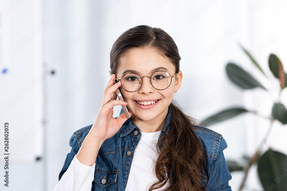 cheerful kid looking at camera while talking on smartphone in office cheerful kid looking at camera while talking on smartphone in office