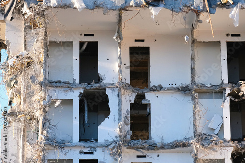 Demolished destructed building ruins. Demolition site in european city. Ruined house on a bright blue sky on a sunny day.