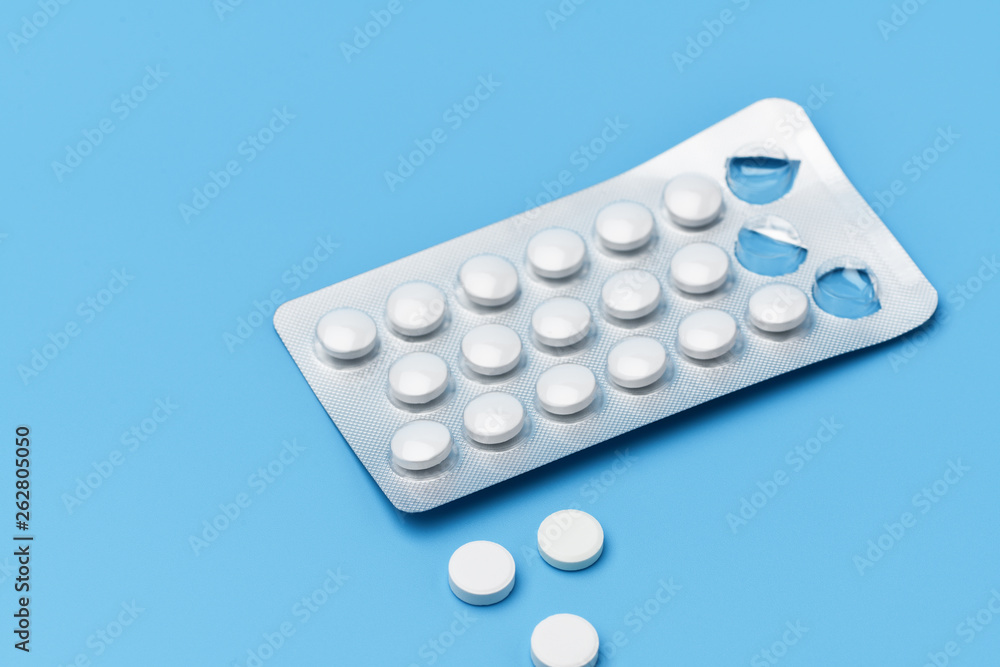 One pack of pills and next are three pills squeezed out on a blue background One pack of pills and next are three pills squeezed out on a blue background