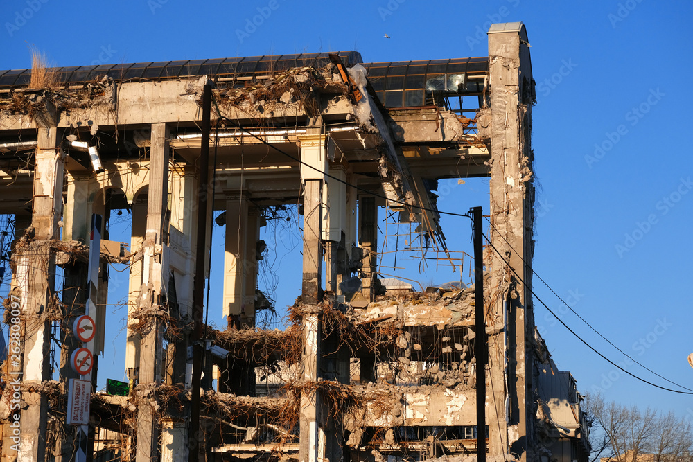 Demolished destructed building ruins. Demolition site in european city. Ruined house on a bright blue sky at sunset