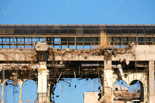 Demolished destructed building ruins. Demolition site in european city. Ruined house on a bright blue sky on a sunny day.