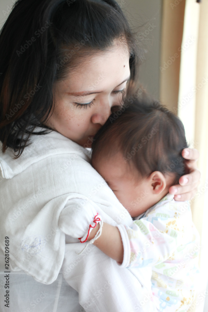 Mom is holding and kissing her baby with love Mom is holding and kissing her baby with love