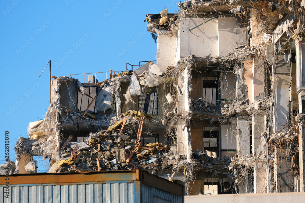 Demolished destructed building ruins. Demolition site in european city. Ruined house on a bright blue sky on a sunny day.