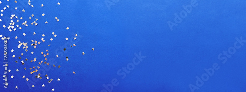 Holiday background with silver star confetti on blue background. Good backdrop for Christmas and New Year cards.