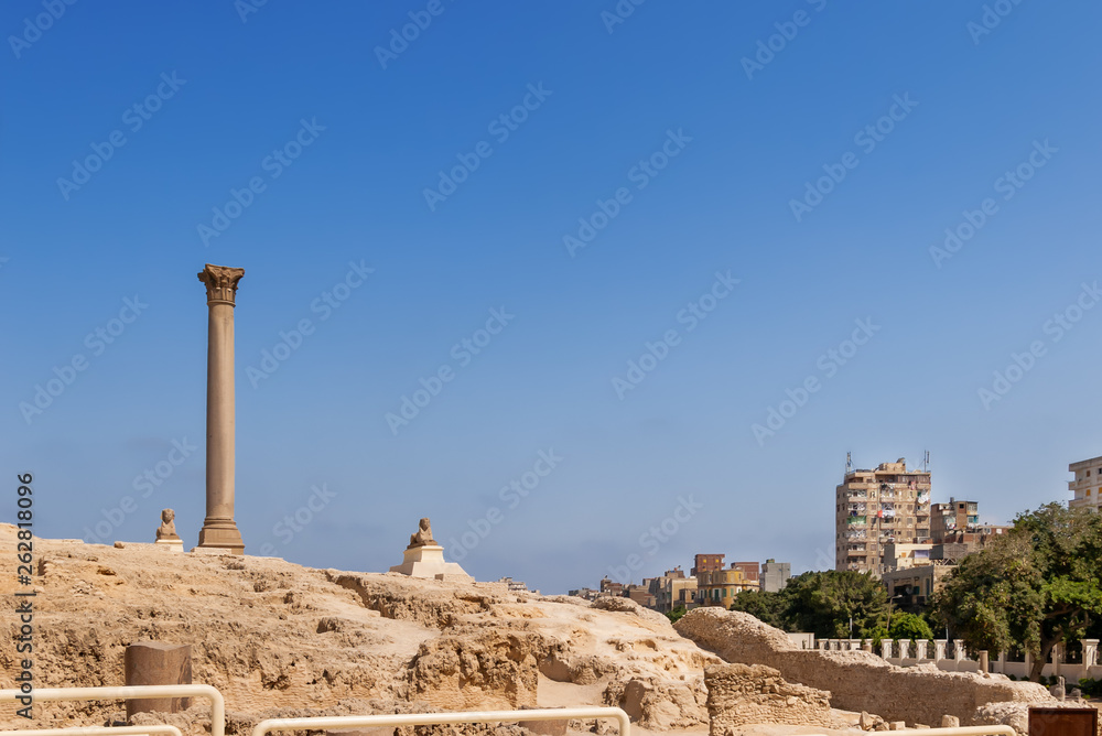 Pompey's Pillar, Roman triumphal column, with two Sphinx statues located at the Serapeum of Alexandria. Ancient architectural landmark in Egypt.