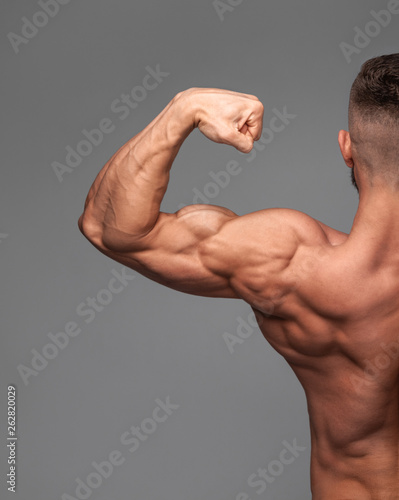Handsome power athletic man bodybuilder demonstrates his biceps.
