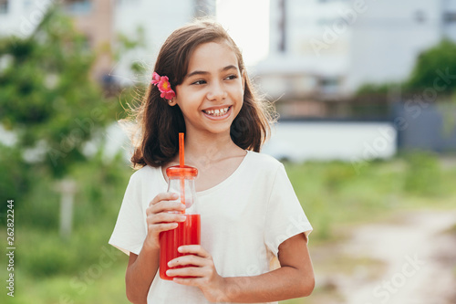 Portrait of young girl drinking juice in the park