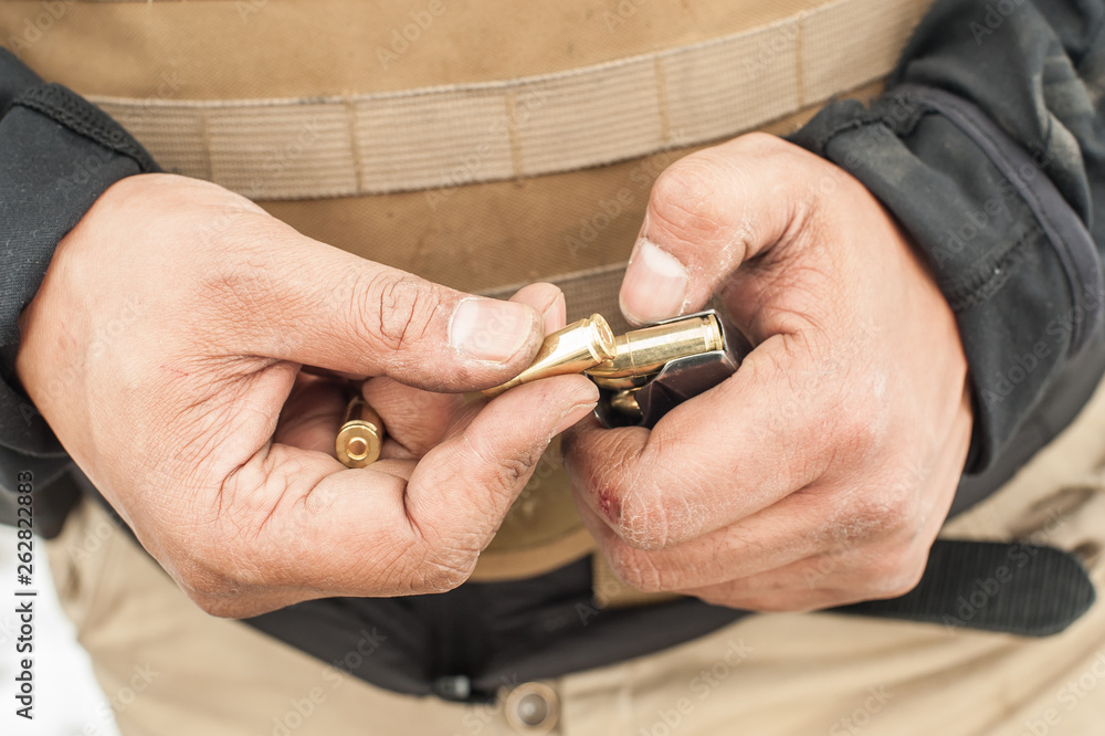 Fototapeta premium View of soldier hands load gun bullets into cartridge clip