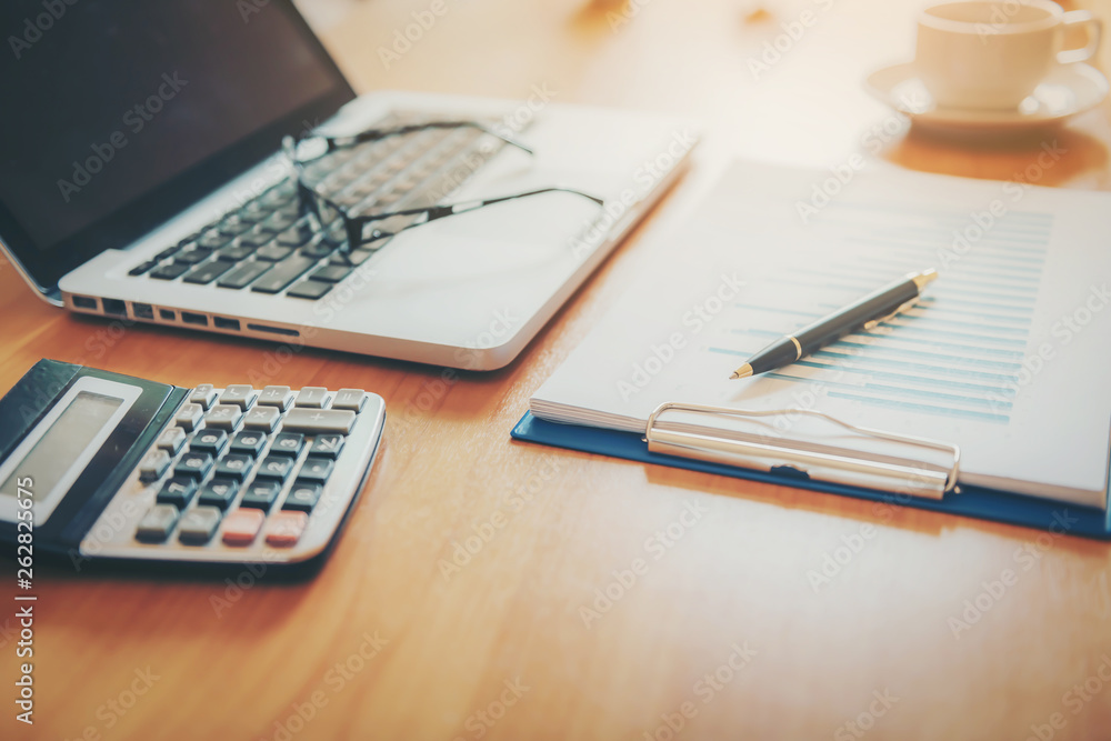 Laptop with financial documents on wooden table Laptop with financial documents on wooden table