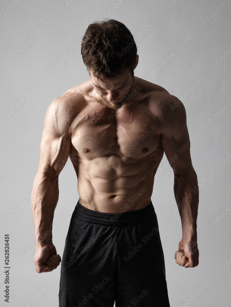 A very tense man with a naked torso looks down on a gray background