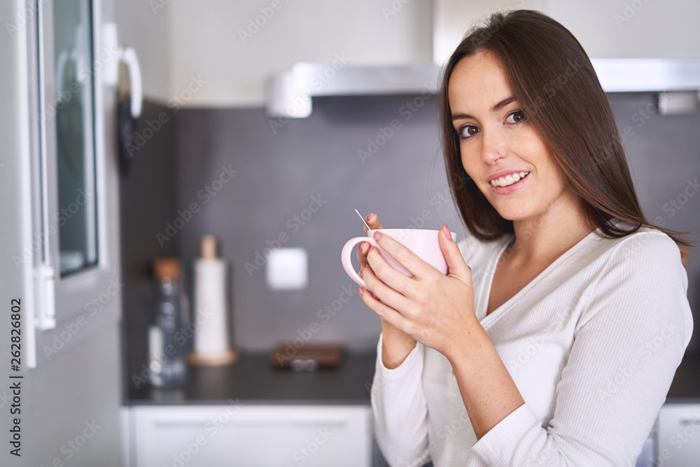 Side view of young attractive woman drinking from mug in modern kitchen at home Side view of young attractive woman drinking from mug in modern kitchen at home