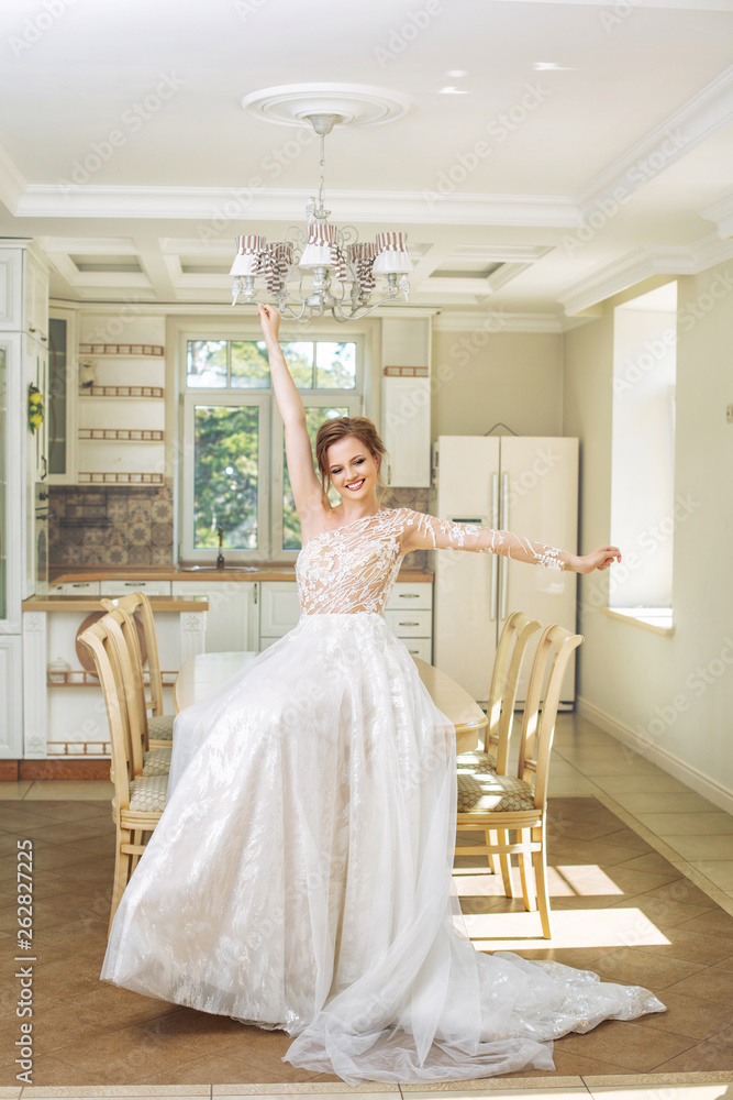 Young beautiful luxury happy bride in a fashionable wedding dress in a vintage interior in the house