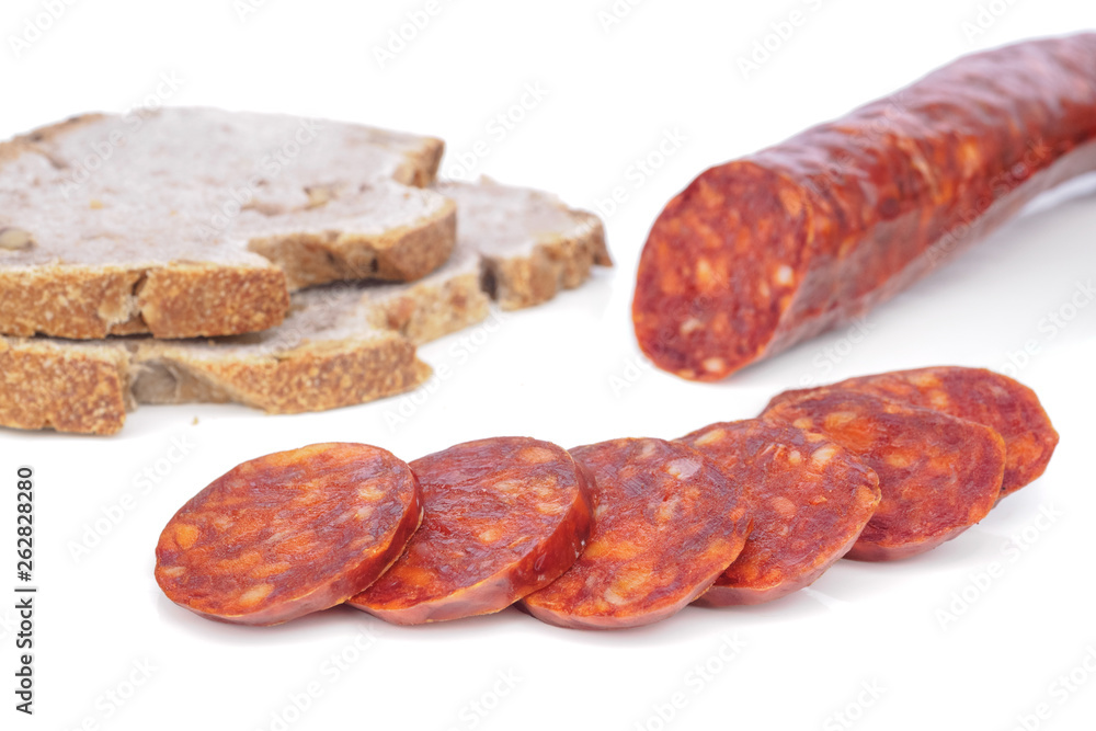 Iberian chorizo, Spanish chorizo or Spanish sausage with its slices placed one on another on a white background with its reflection with rustic bread Iberian chorizo, Spanish chorizo or Spanish sausage with its slices placed one on another on a white background with its reflection with rustic bread