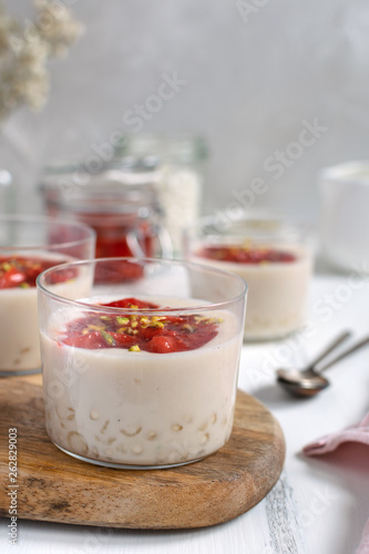 Healthy vegan dairy free dessert - tapioca pearls pudding with coconut milk and strawberry chia jam close up  served in glass jar