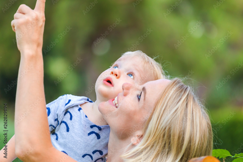 Obraz premium Mom shows something in the sky to her little baby boy