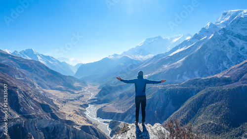 Canvastavla Man wearing a beanie and blue jumper, spreads his arms wide, breathing deeply the fresh mountain air