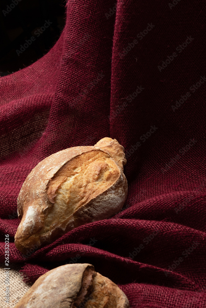 two loaves of bread on the table against the background of colorful burlap,still life, closeup two loaves of bread on the table against the background of colorful burlap,still life, closeup
