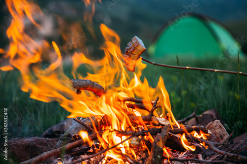 Fried bacon at campfire while camping outdoors.