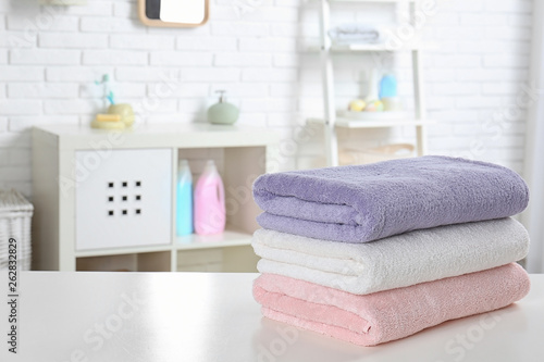 Stack of fresh towels on table in bathroom. Space for text