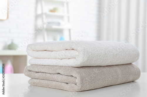 Stack of fresh towels on table in bathroom  closeup. Space for text