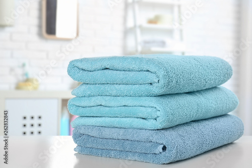 Stack of fresh towels on table in bathroom, closeup