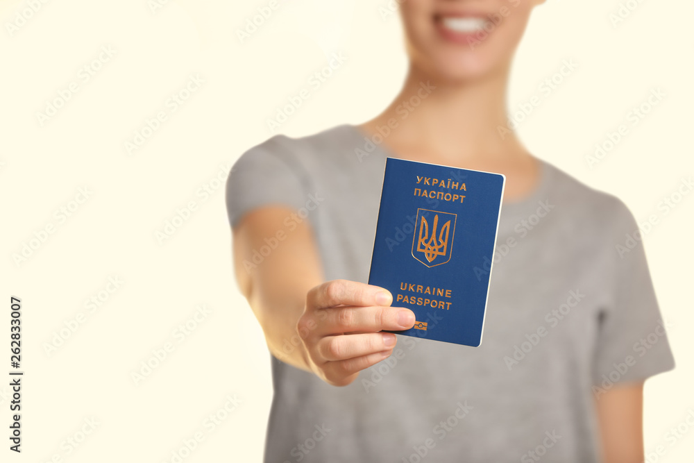 Woman holding Ukrainian travel passport against blurred background, closeup with space for text. International relationships