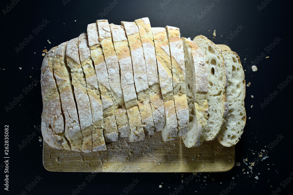 Sliced bread on top of wooden board texture with black background. Sliced bread on top of wooden board texture with black background.