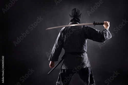 Photo Ninja samurai with katana stands with his back to the viewer.