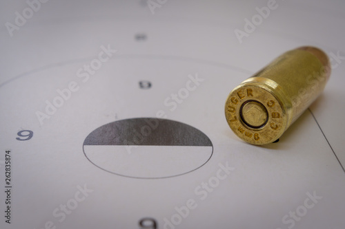 A 9mm bullet closeup with a paper target in the background photo