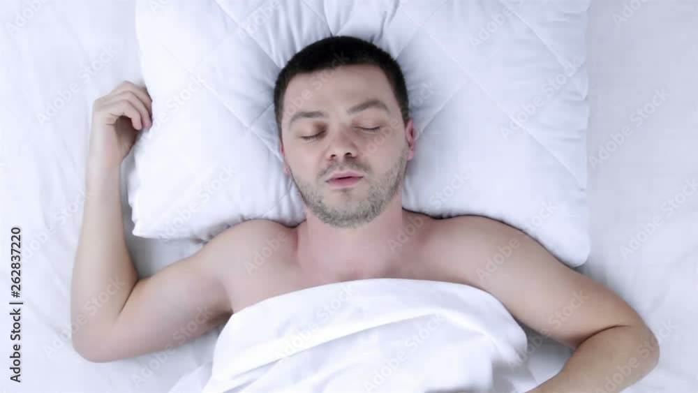 Top view. Man waking up in a comfortable bed Top view. Man waking up in a comfortable bed