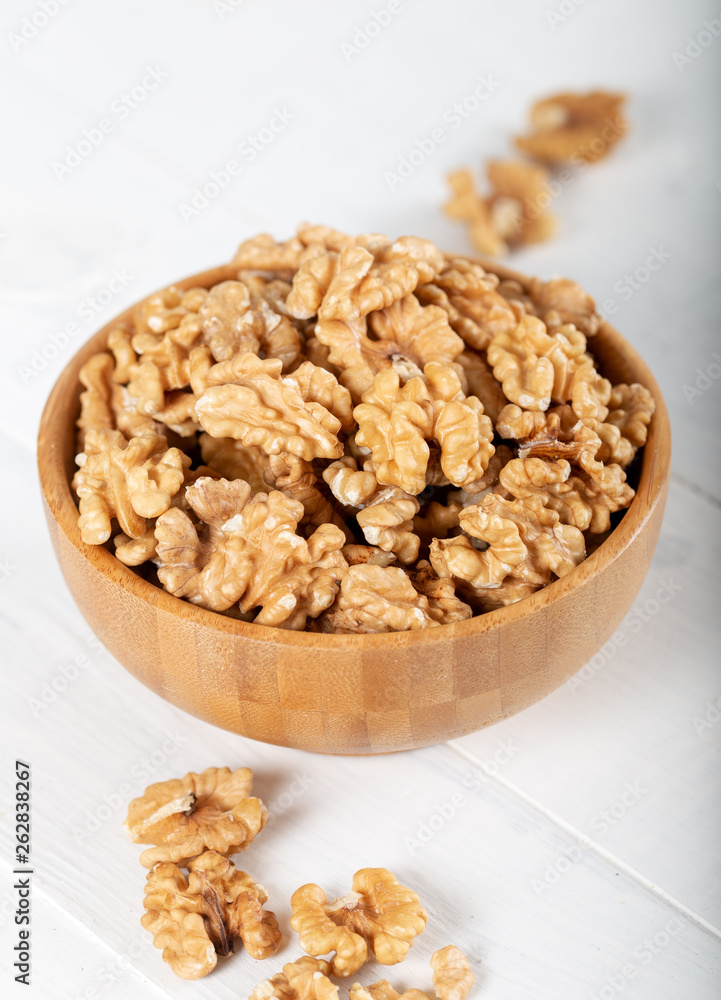 Walnut kernels in a wooden bowl on white background. Walnut kernels in a wooden bowl on white background.