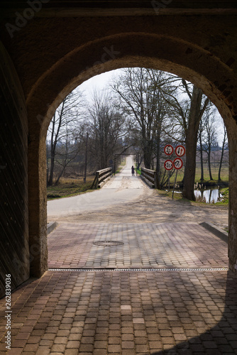 View of the wooden bridge across the moat around the Shlokenbek estate in Latvia. 7 April 2019. photo