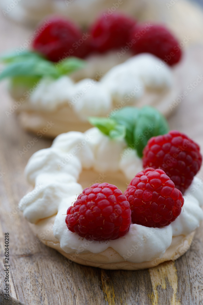 Mini Pavlova dessert with raspberries and mint. Served on a wooden board, high resolution Mini Pavlova dessert with raspberries and mint. Served on a wooden board, high resolution