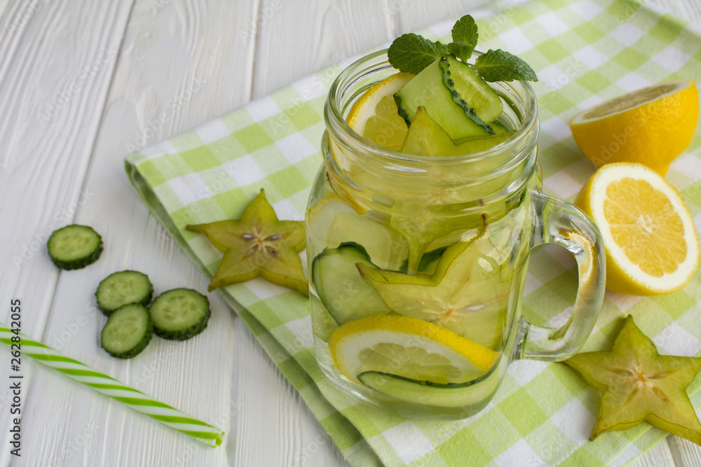 Detox or infused water with cucumber, carambola and lemon on the white wooden background Detox or infused water with cucumber, carambola and lemon on the white wooden background