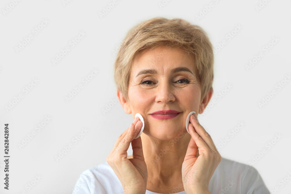 stylish beautiful elderly woman with a short haircut on a white background cleans face stylish beautiful elderly woman with a short haircut on a white background cleans face