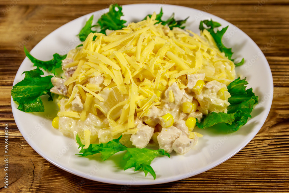 Festive salad with chicken breast, sweet corn, canned pineapple, cheese and mayonnaise on wooden table Festive salad with chicken breast, sweet corn, canned pineapple, cheese and mayonnaise on wooden table