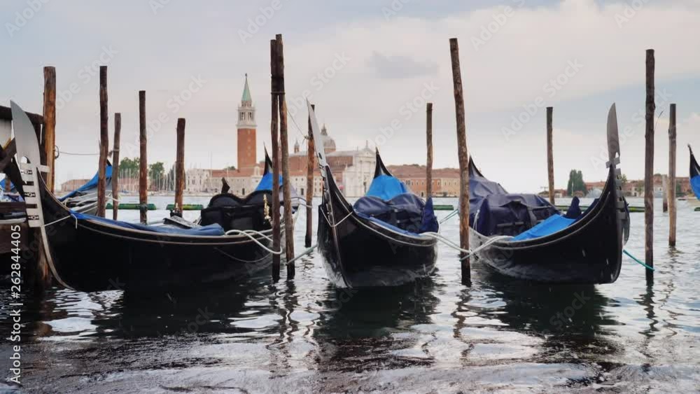 Three gondolas are moored against the background of the Venetian city line Three gondolas are moored against the background of the Venetian city line