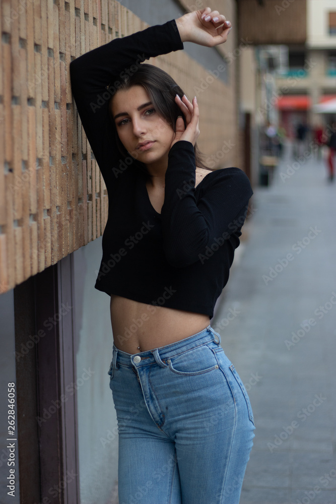 Hipster beautiful girl wearing blank t-shirt and jeans posing against rough street wall, minimalist urban clothing style, mockup for tshirt