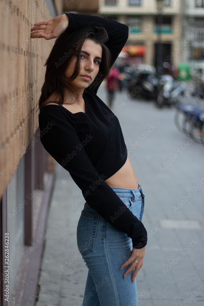 Hipster beautiful girl wearing blank t-shirt and jeans posing against rough street wall, minimalist urban clothing style, mockup for tshirt